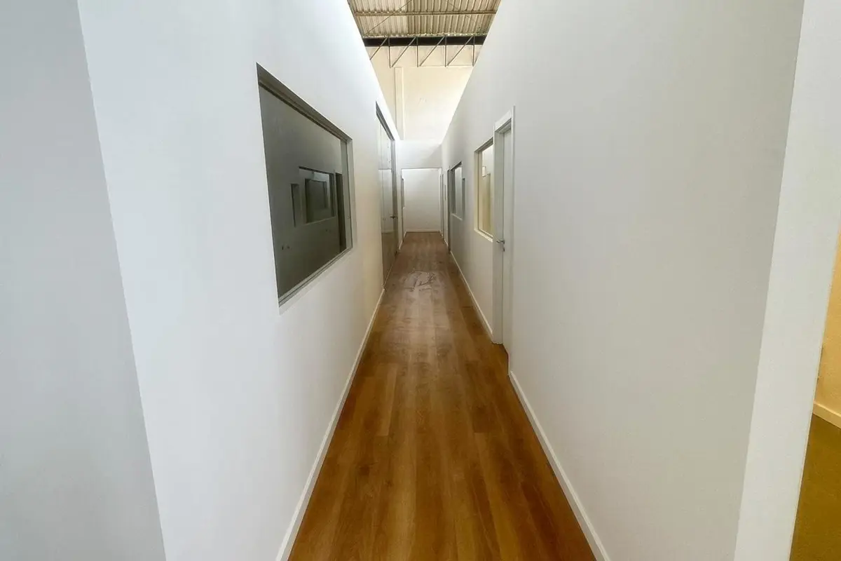 Corredor branco de piso em madeira sob uma cobertura metálica, no Projeto Sacavém