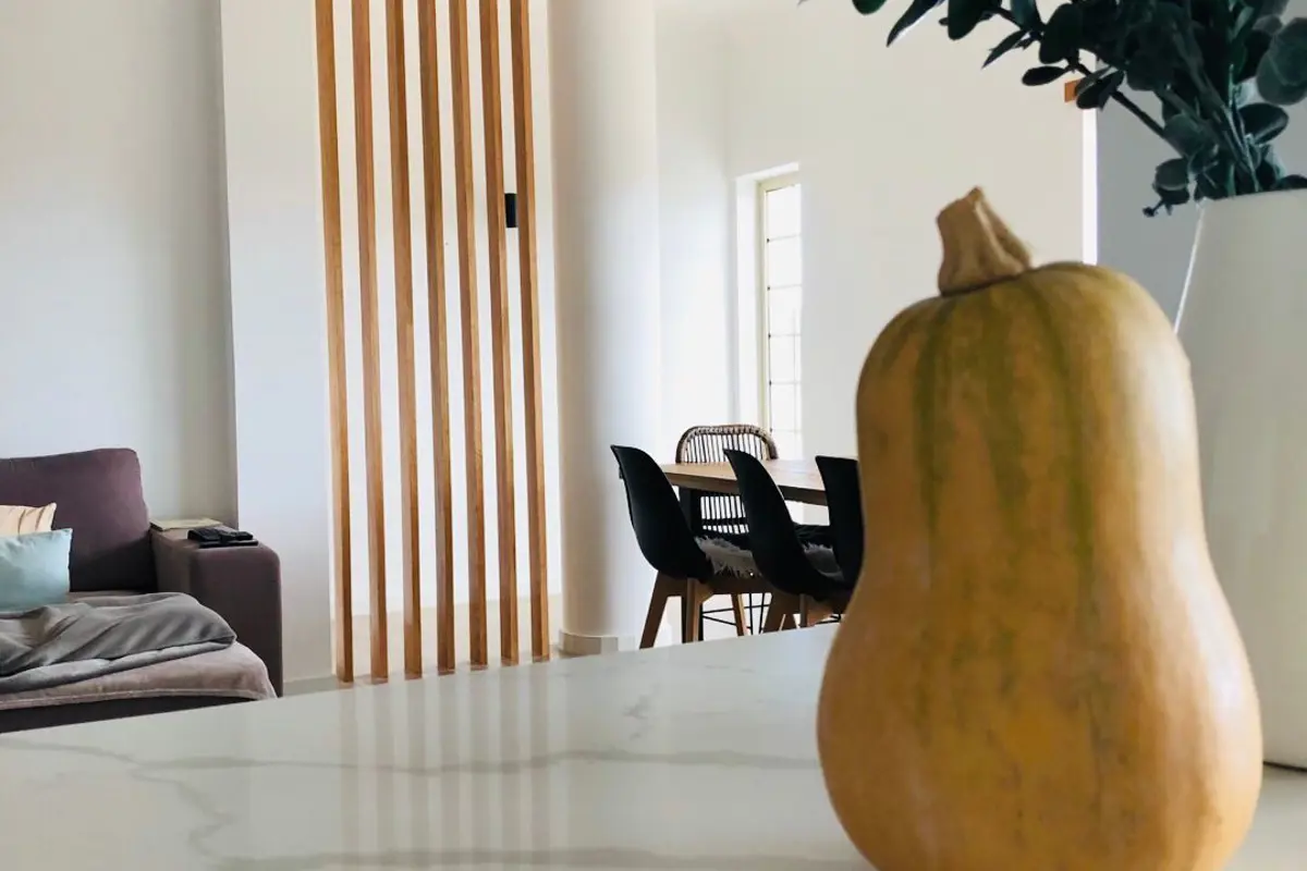 Bancada de mármore a separar a sala da zona de jantar, com um ripado de madeira ao fundo