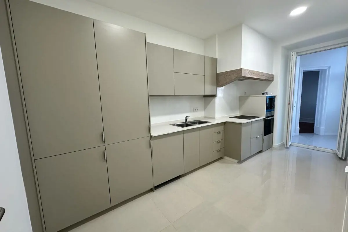 Cozinha nova em tons de areia, com bancada clara e forno encastrado, no Projeto Lisboa